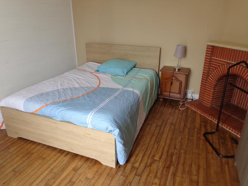uma cama num quarto com piso em madeira em Chambre chez l'habitant em Questembert