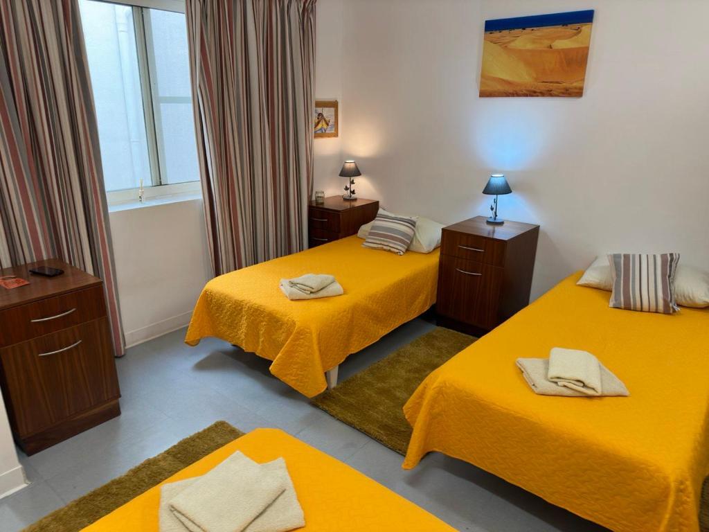 een kamer met 3 bedden met gele lakens bij Malta Crown guesthouse in St Julian's