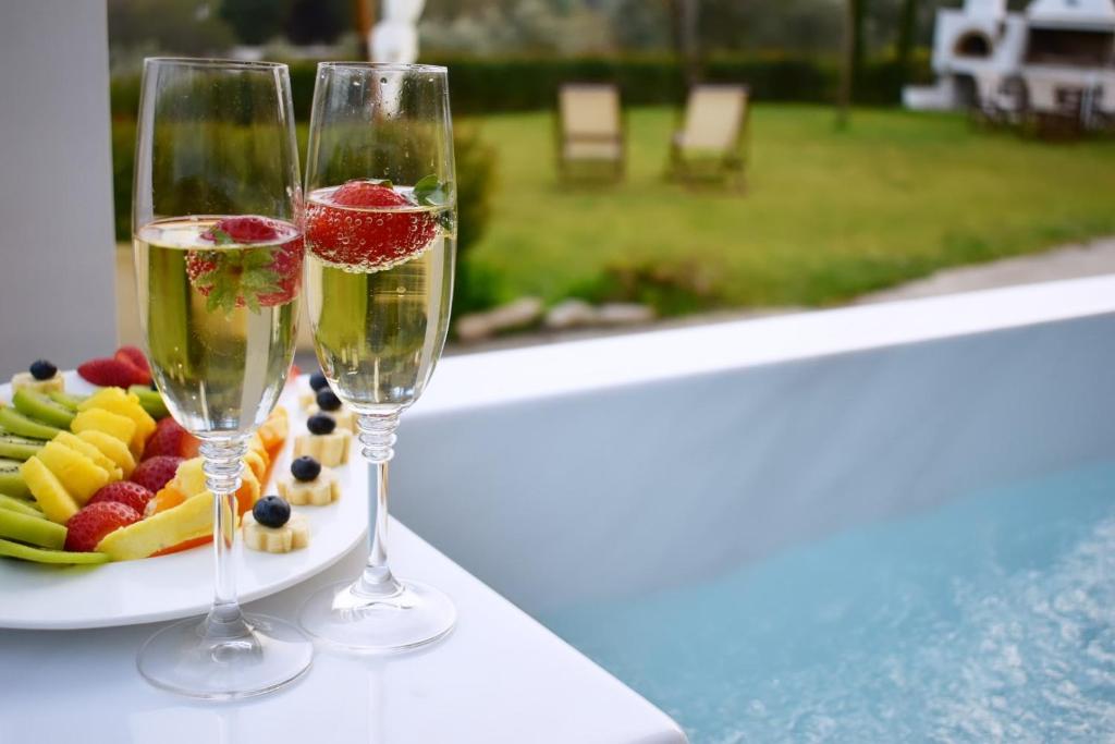 two glasses of champagne next to a plate of fruit at Anemi Superior Deluxe Suite in Kolios