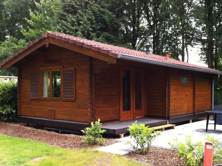 a small wooden cabin with a porch in a yard at Geniet van het leven.. in De boomklever in Diffelen