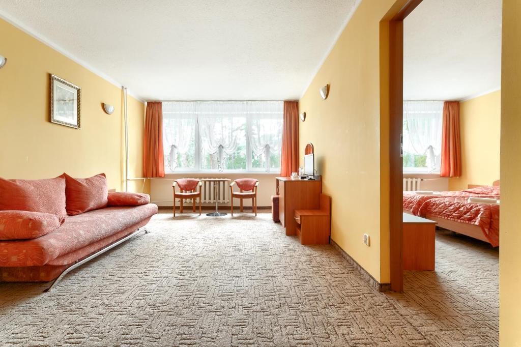 Habitación de hotel con sofá y cama en Hotel Bocianie Gniazdo, en Niechorze