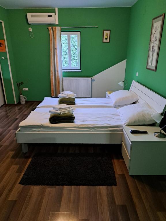 a bedroom with a large bed with green walls at Rooms Modrušan in Slunj