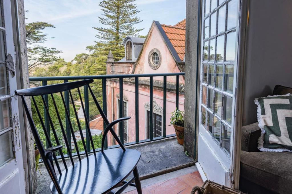 uma cadeira sentada numa varanda com vista para uma igreja em Cozy Little Romm on Palace Patio em Sintra