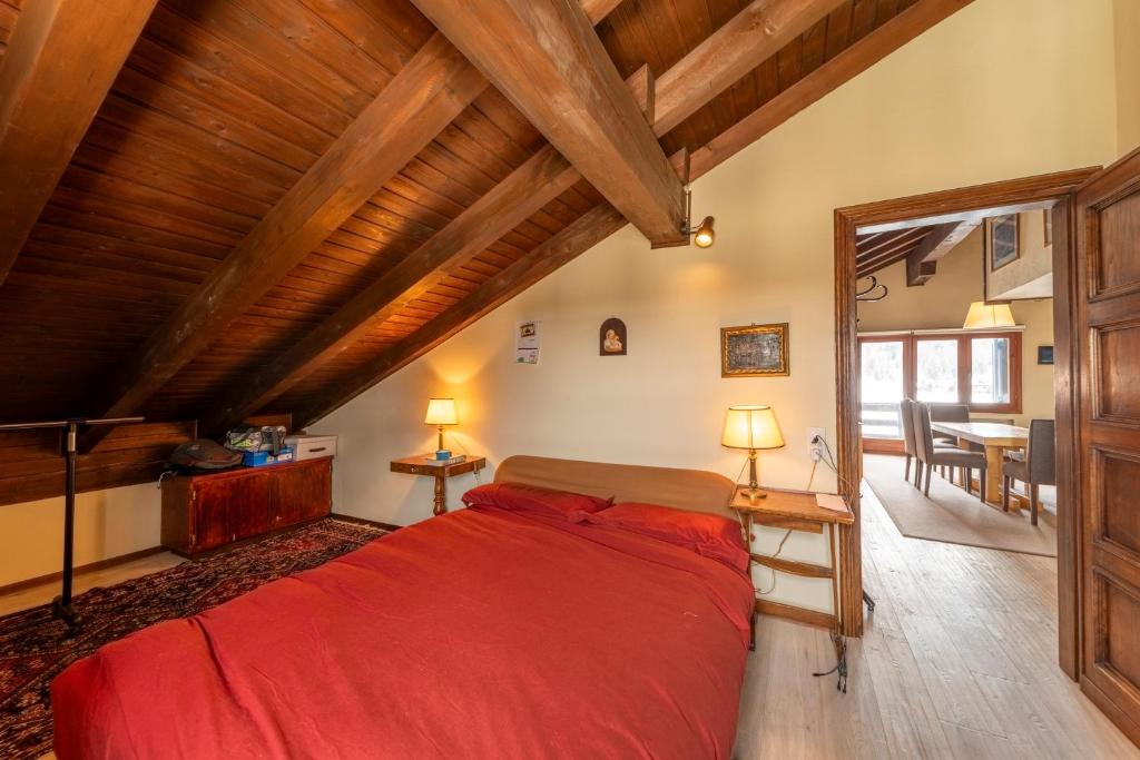 Chesa Ste Attic - Celerina في سيليرينا: غرفة نوم بسرير احمر في غرفة بسقوف خشبية