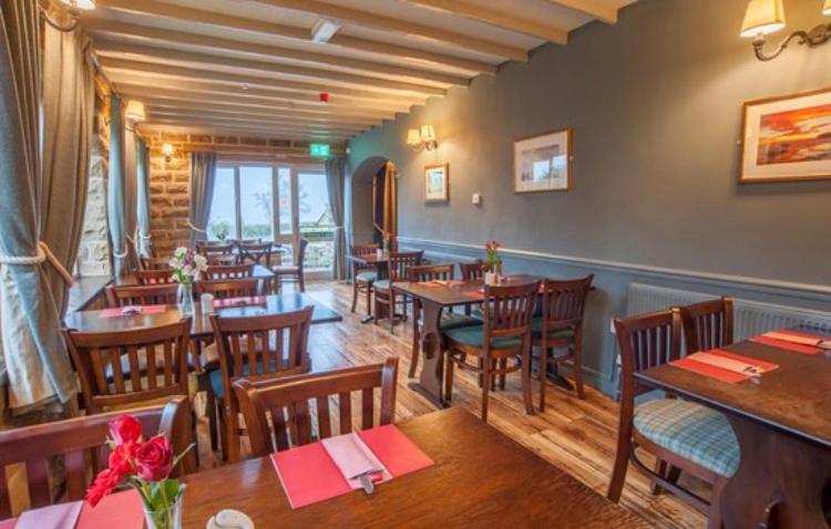 a restaurant with wooden tables and wooden chairs at The Plough in Sleights