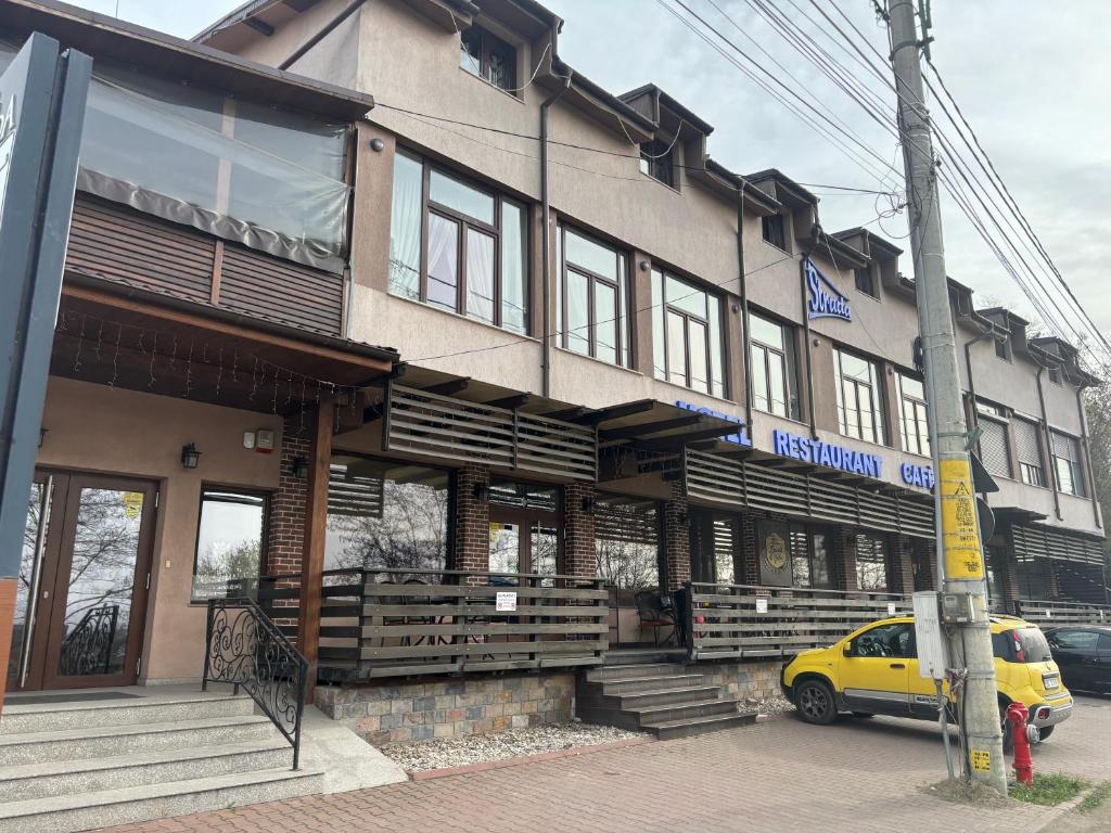 un bâtiment avec une voiture jaune garée devant lui dans l'établissement La Strada, à Onești