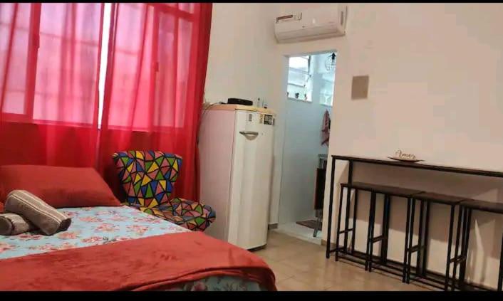 a bedroom with a bed and a refrigerator and a window at Apartamento Lapa in Rio de Janeiro