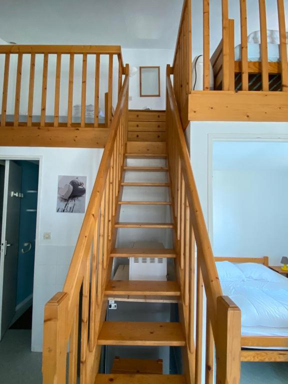 a wooden staircase in a room with a bed at Maisonnette dans résidence vacances, à 200m de la plage in Bretignolles-sur-Mer