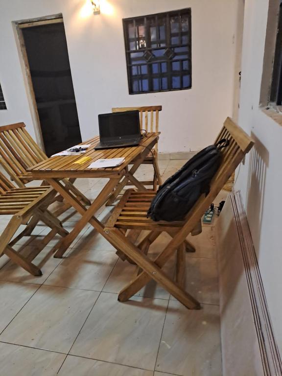una mesa de madera y sillas con un ordenador portátil. en Aberdare white camp house kenya, en Ndaragwa