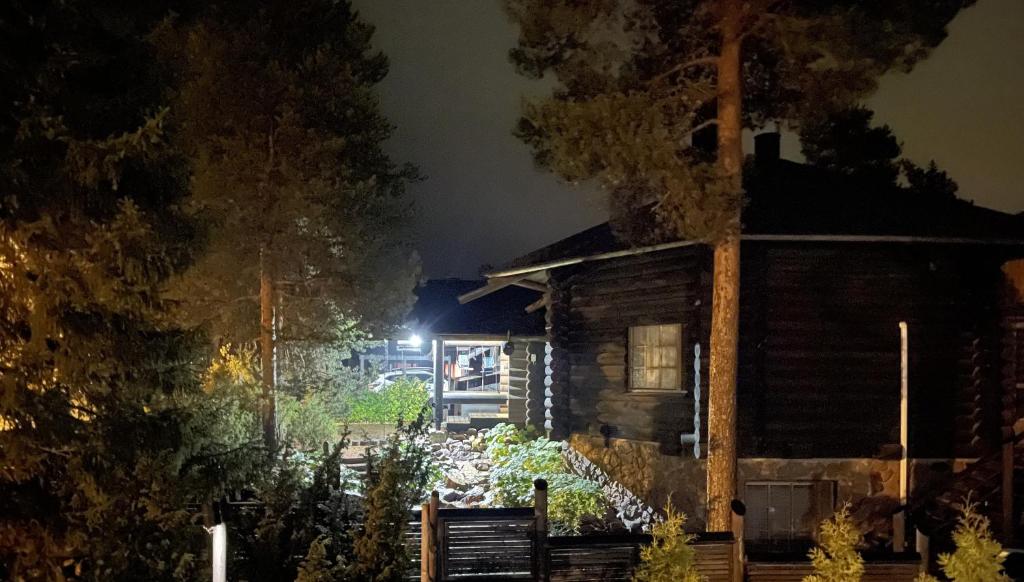 een blokhut 's nachts met rook die eruit komt bij Log home near Santa in Rovaniemi
