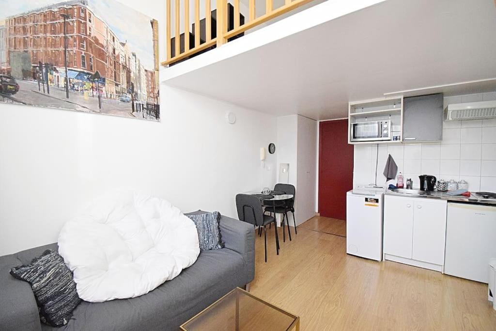 un salon avec un canapé et une cuisine dans l'établissement Beau studio mezzanine meublé, à Courbevoie