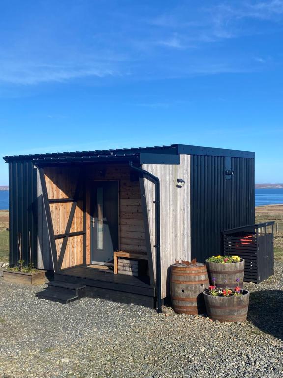 a smallshed with two pots in front of it at Unique luxurious cabin on sea view working croft in Garrabost