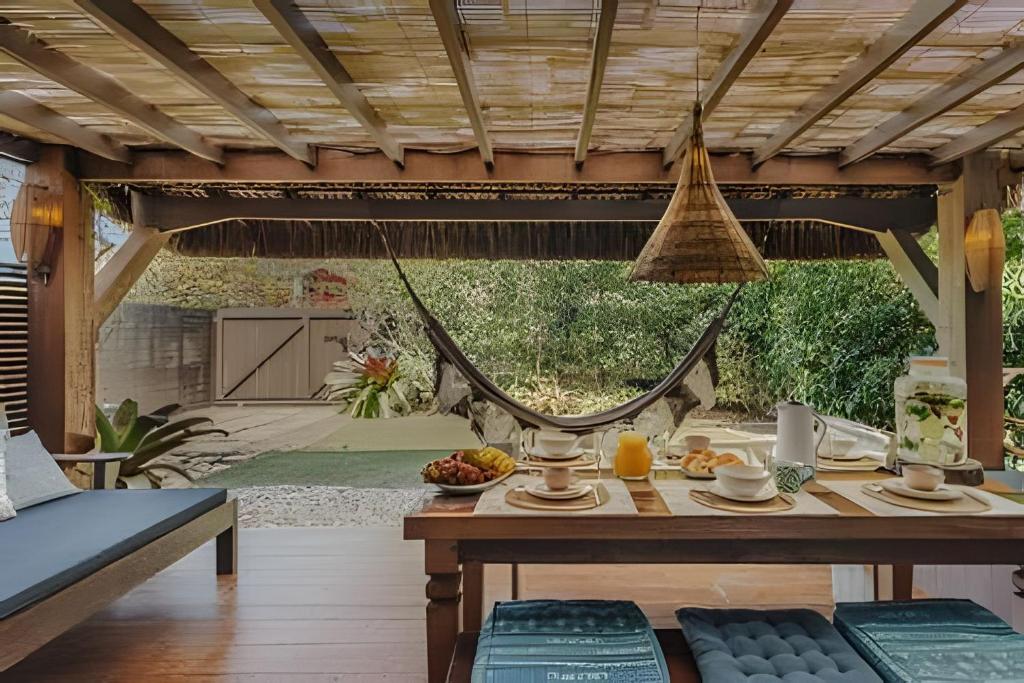 a patio with a table and a hammock at Casa Thai Linda na Praia in Barra de Ibiraquera