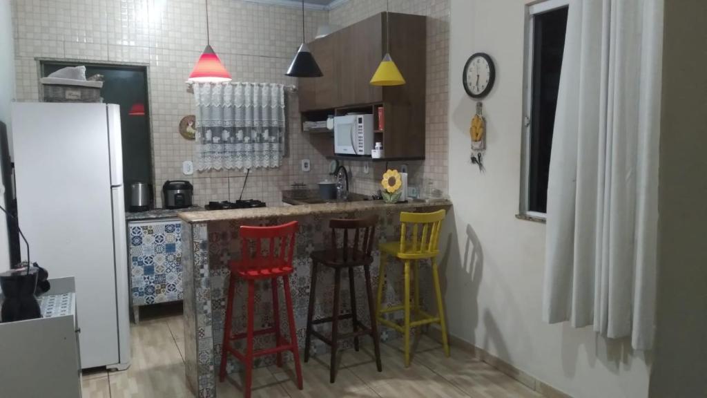 a kitchen with colorful stools at a kitchen counter at Casa tipo sobrado. in Arraial do Cabo