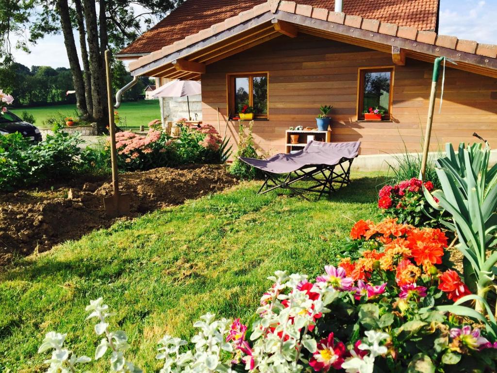 einen Garten mit einem Haus mit einem Stuhl und Blumen in der Unterkunft Gîte Les Cigognes in Orchamps-Vennes