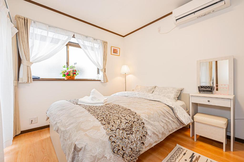 a white bedroom with a bed and a window at Himawari in Tokyo