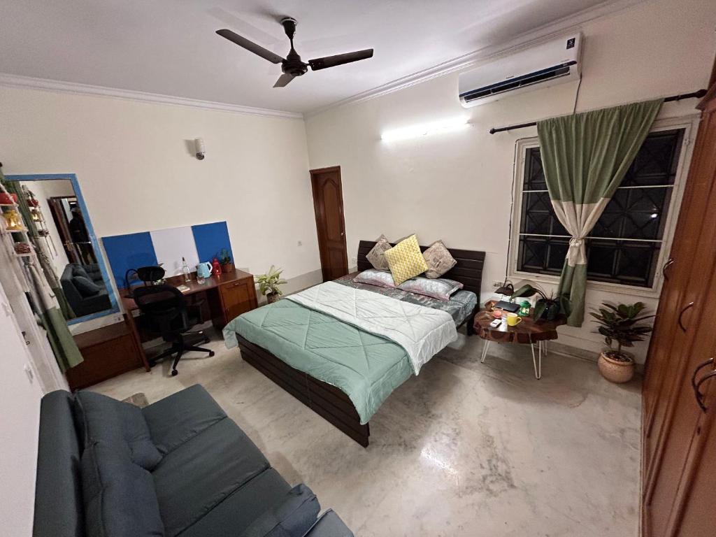 a bedroom with a bed and a couch and a desk at Artist Abode in Bangalore