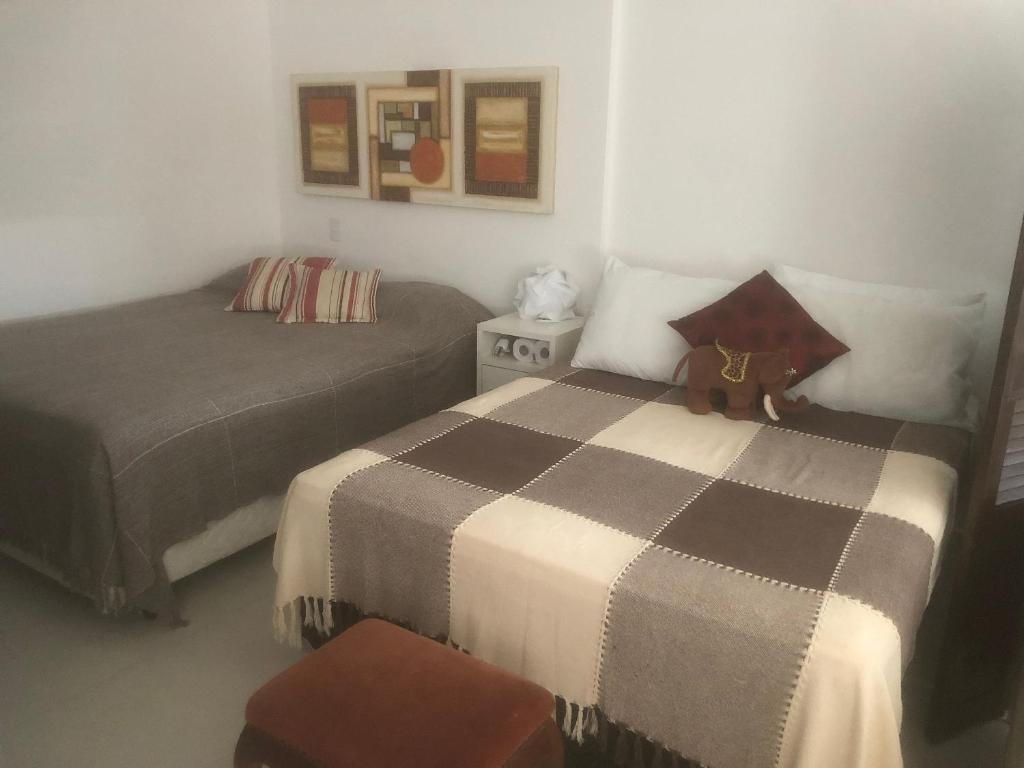 un dormitorio con 2 camas y un osito de peluche sentado en una cama en Studio Residencial Montevideo, en Osório