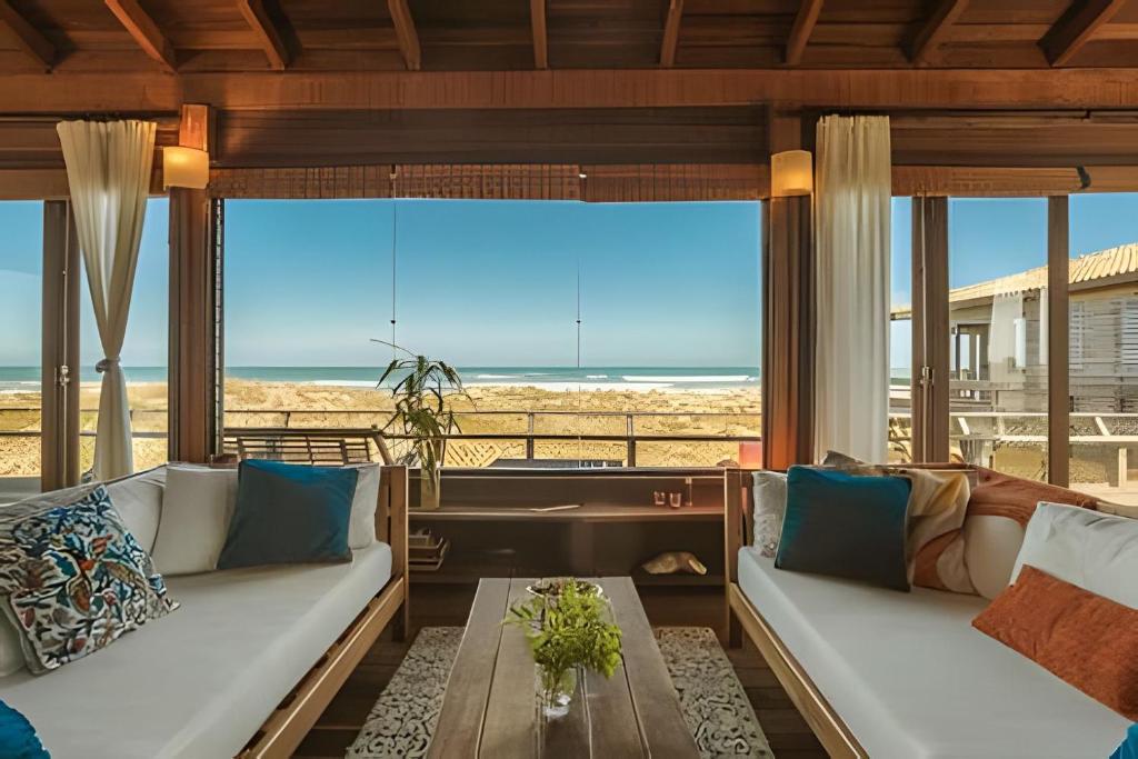 a living room with couches and a view of the beach at Casa dos Imbês - Frente ao Mar in Barra de Ibiraquera