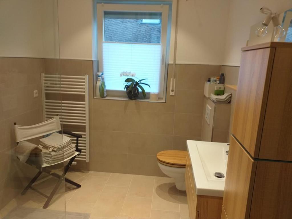 a bathroom with a toilet and a window and a chair at Helle 4 ZKB mit Balkon in Wittlich in Wittlich