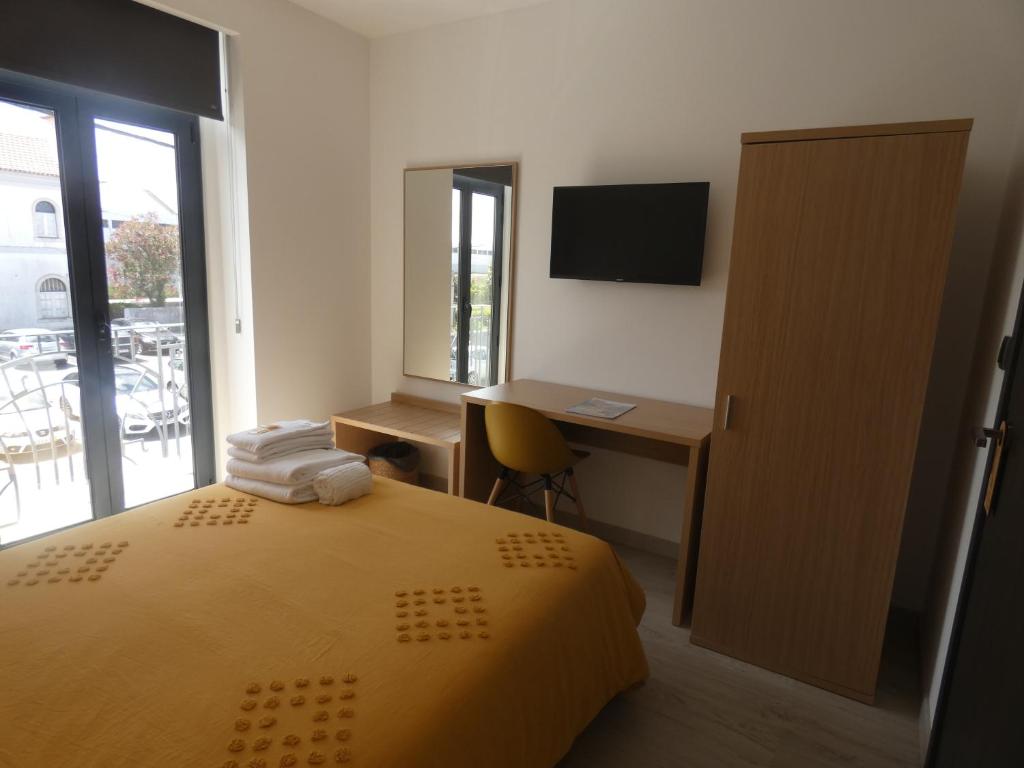 a bedroom with a bed and a desk and a television at Pinhal Litoral in Marinha Grande