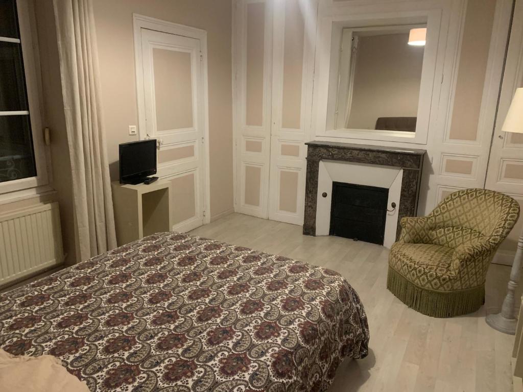 - une chambre avec un lit, une chaise et une cheminée dans l'établissement Chez Isa, au Mans