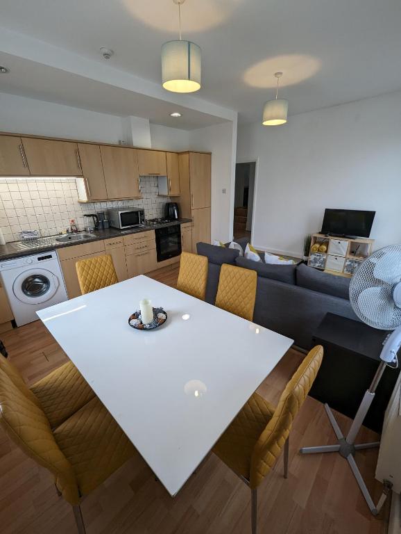 格雷夫森德的住宿－2 bedroom apartment in Gravesend 10 mins walk from train station with free parking，厨房以及带白色桌椅的起居室。