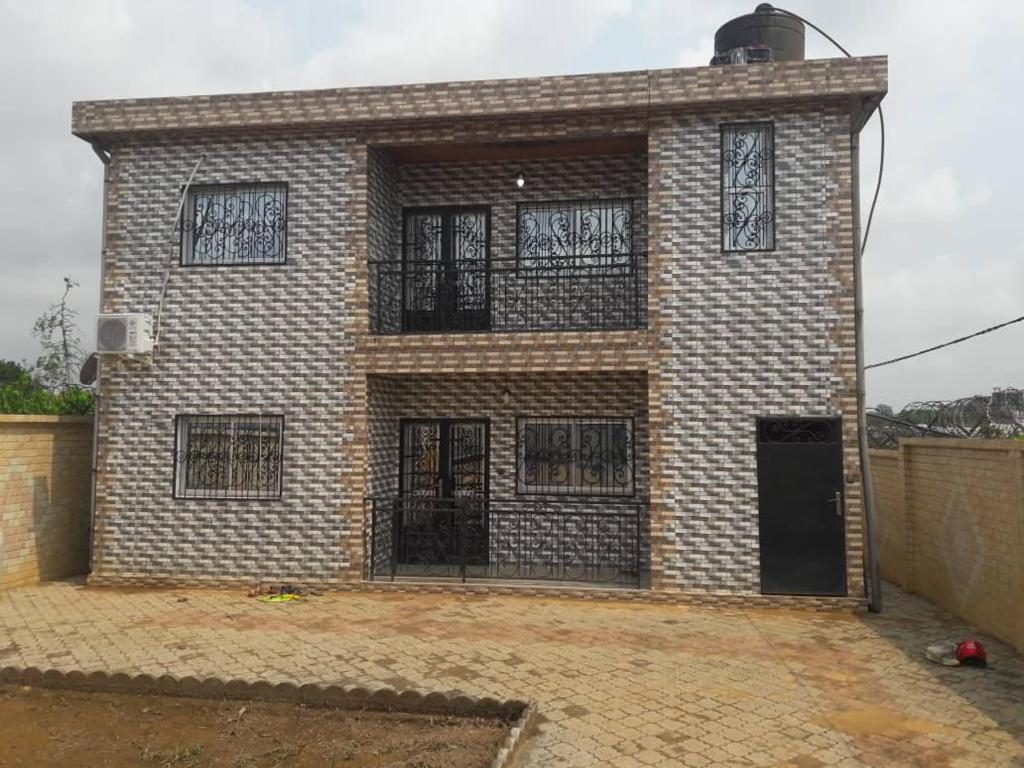 a brick building with bars on the windows at appartement meublé à Yansoki douala in Ngori