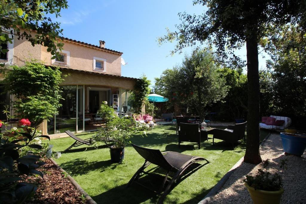 een tuin met stoelen en een tafel en een huis bij Valbonne - Villa dans le domaine privé Val d'Azur avec piscine, tennis in Valbonne