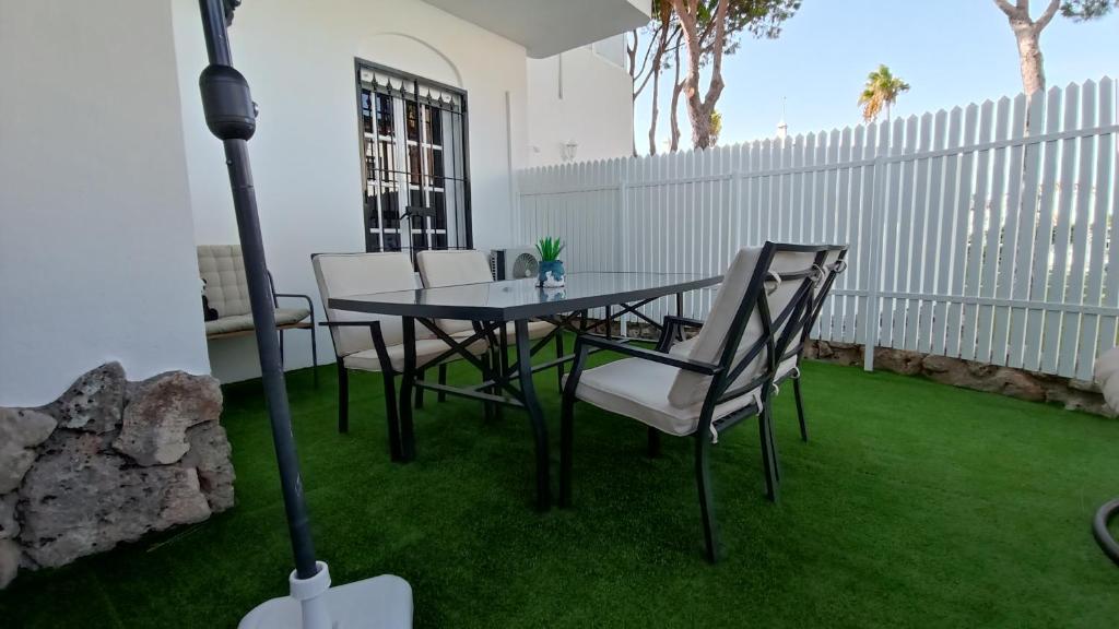 een patio met een tafel en stoelen op het gras bij Apartamento La Barrosa - Chiclana - Urb. Pinar Atlántico in Chiclana de la Frontera