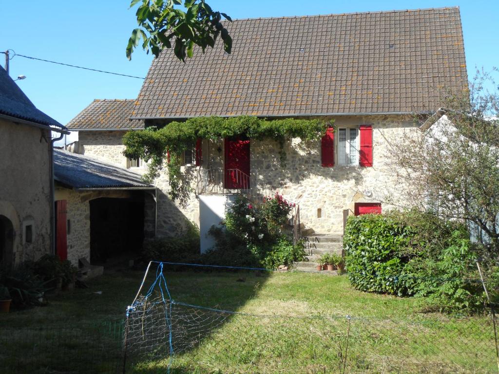 ein Haus mit roten Fenstern und einem Netz im Hof in der Unterkunft Gîte à la ferme in Pachins