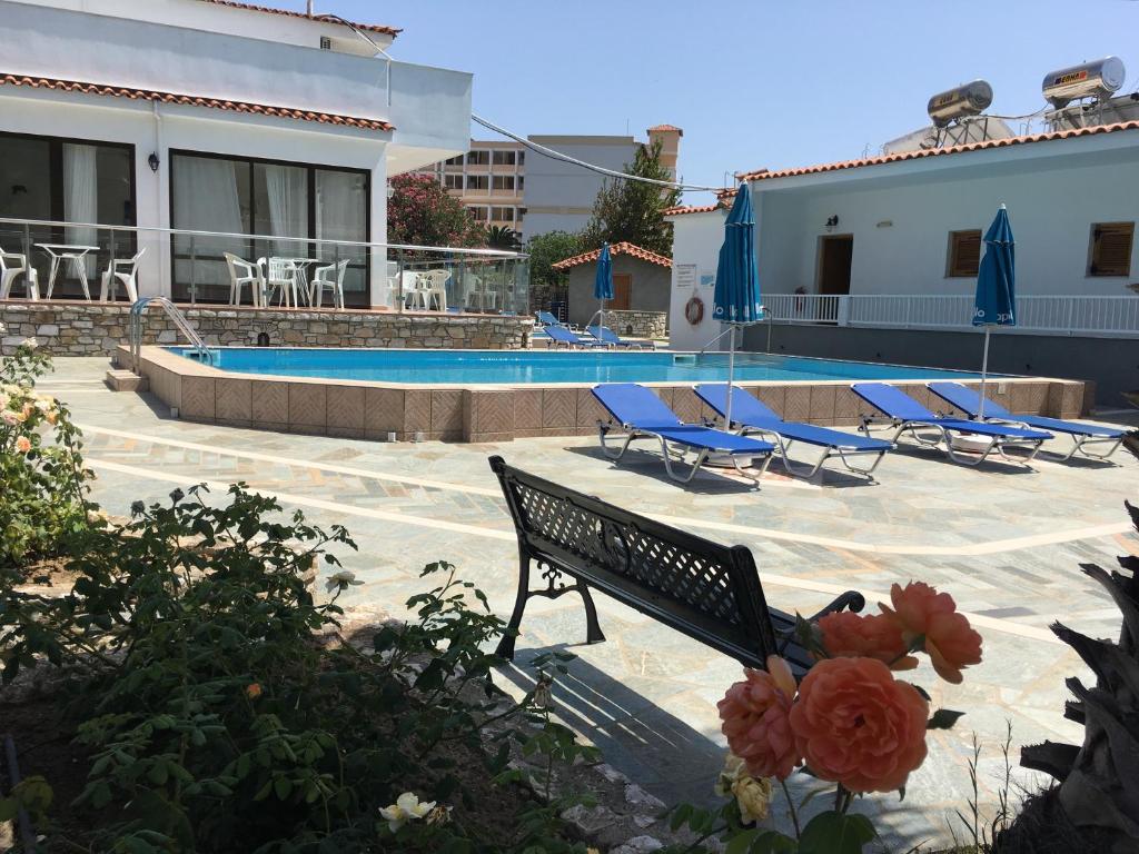 a pool with chairs and a bench next to a building at Hotel Suzanna in Achladies