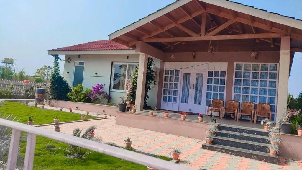 une petite maison blanche avec une terrasse couverte et des chaises dans l'établissement NATURE NEST HOMESTEAD, à Baihar