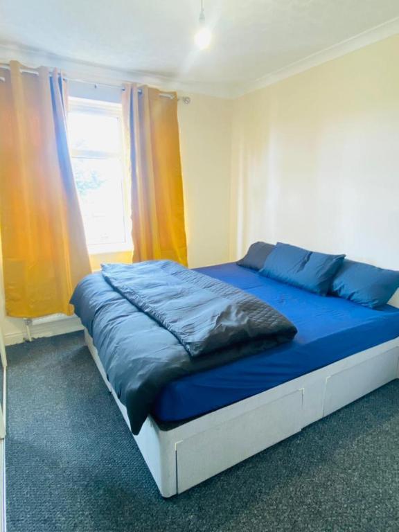 a bedroom with a bed with blue sheets and a window at Instant Lodge in Leicester