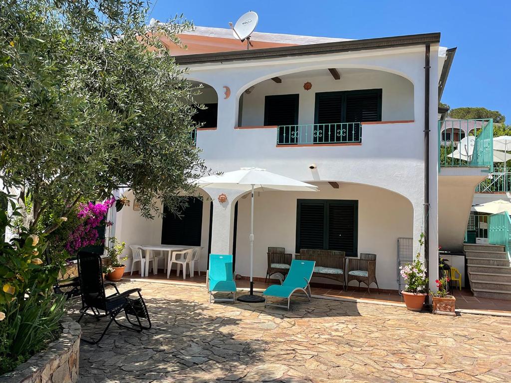een wit huis met stoelen en een parasol bij Mare Turchese in Cala Liberotto