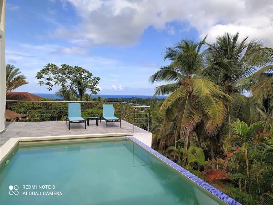 uma piscina com duas cadeiras e o oceano em Villa vue sur Océan em Las Terrenas