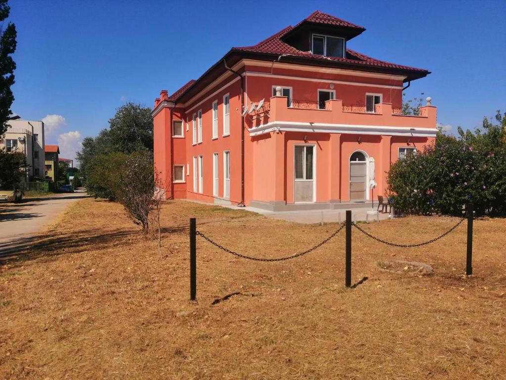 a large red building with a fence in front of it at Vila Puskin - Eforie Sud in Eforie Sud