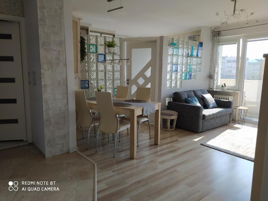 a dining room and living room with a table and chairs at Apartament SUNNY in Gdynia