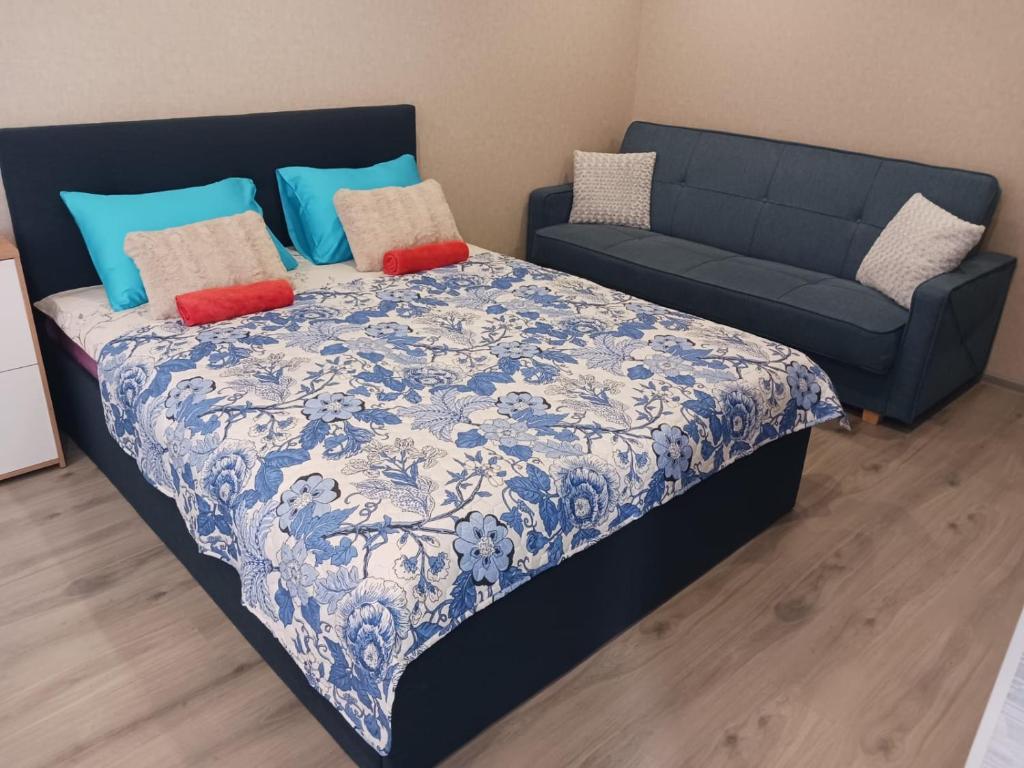 a bed with a blue and white blanket and a couch at Kandavas Apartments in Daugavpils