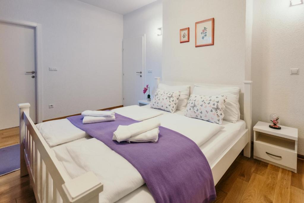 sypialnia z dużym białym łóżkiem i fioletowym kocem w obiekcie Apartment Vijećnica w Sarajewie