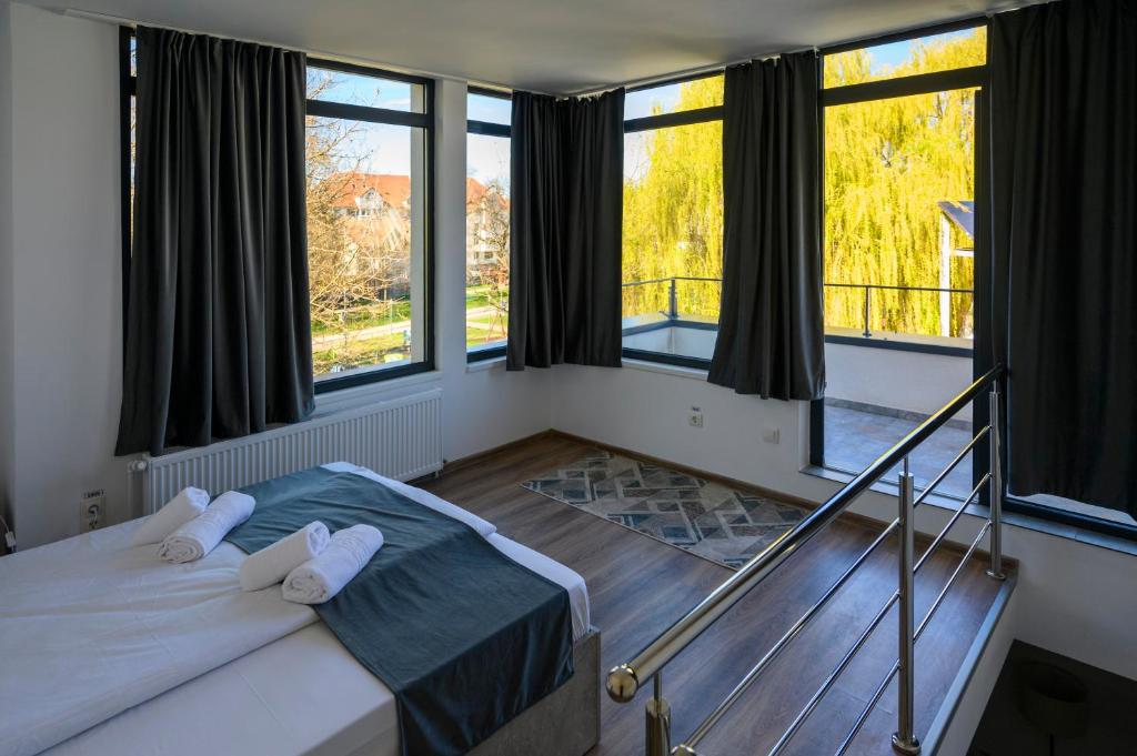 a bedroom with a bed and large windows at Casa EMA in Bistriţa