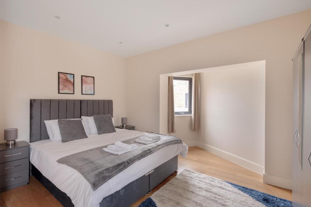 Morden的住宿－Charming Two-Bedroom Retreat in Morden SM4, London，白色的卧室设有一张大床和一个窗户