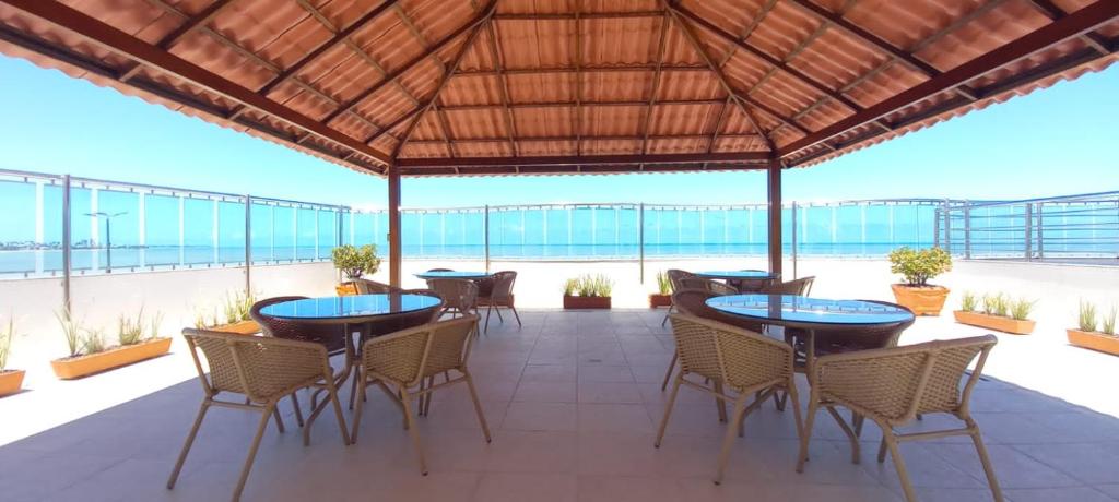 een patio met tafels en stoelen en het strand bij Flat Manaíra Palace Beira Mar in João Pessoa