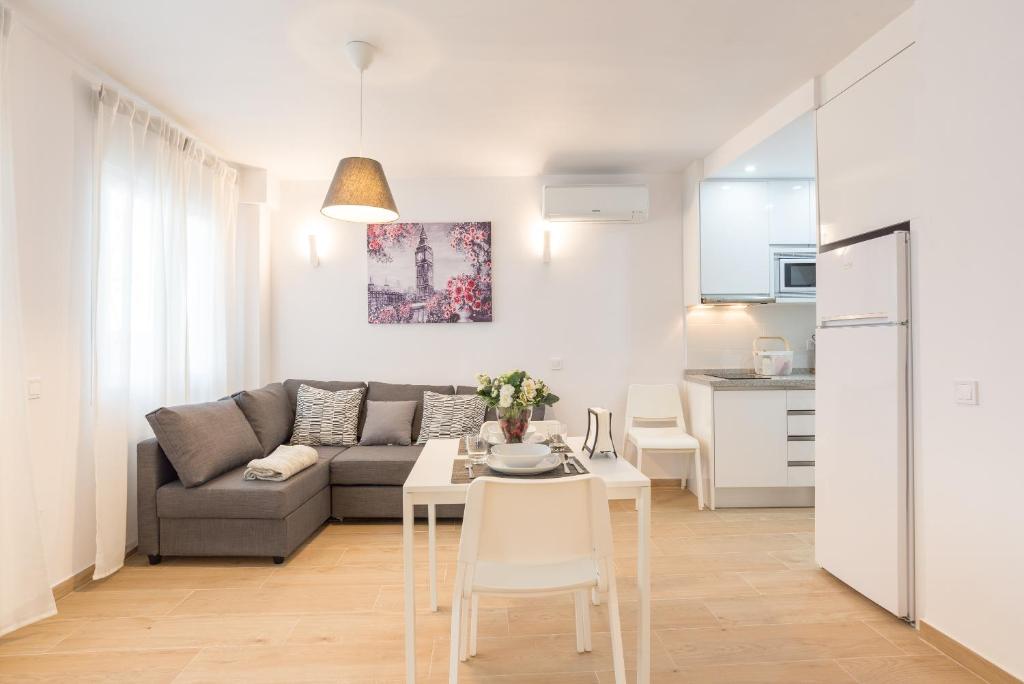 sala de estar con sofá, mesa y cocina en Nordik Apartments Urban - Perchel "Skogar", en Málaga
