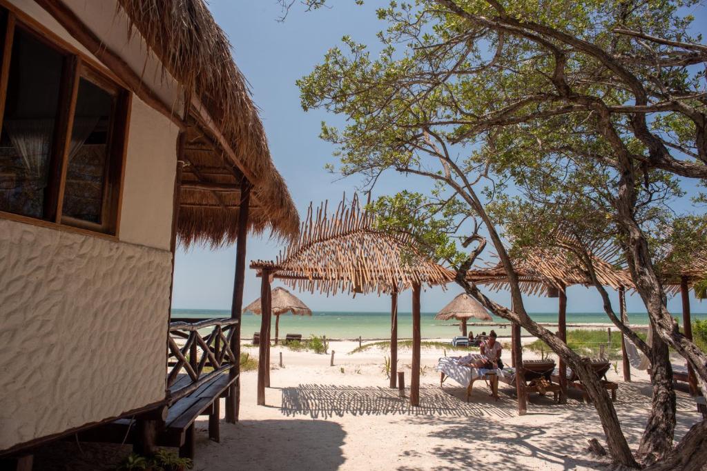un edificio en la playa con sillas y sombrillas en Hotel Casa Takywara, en Isla Holbox