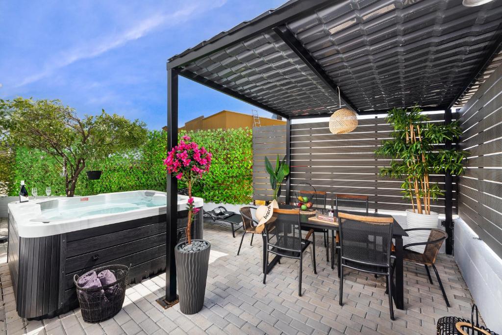 un patio con bañera de hidromasaje, mesa y sillas en Evi's Afandou Suite en Afantou
