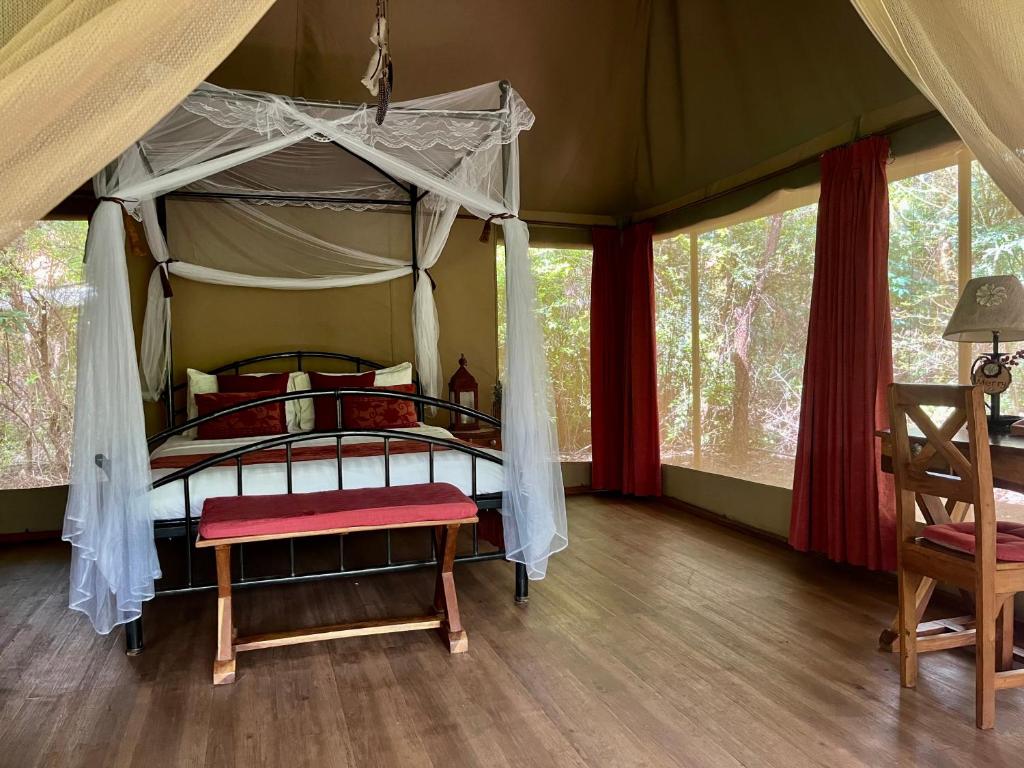 1 dormitorio con cama con dosel en una tienda de campaña en Ikweta Safari Camp, en Maua
