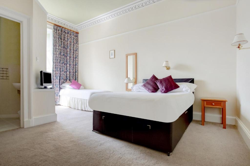 a hotel room with a large white bed with purple pillows at OYO Kirkconnel Hall Hotel in Ecclefechan
