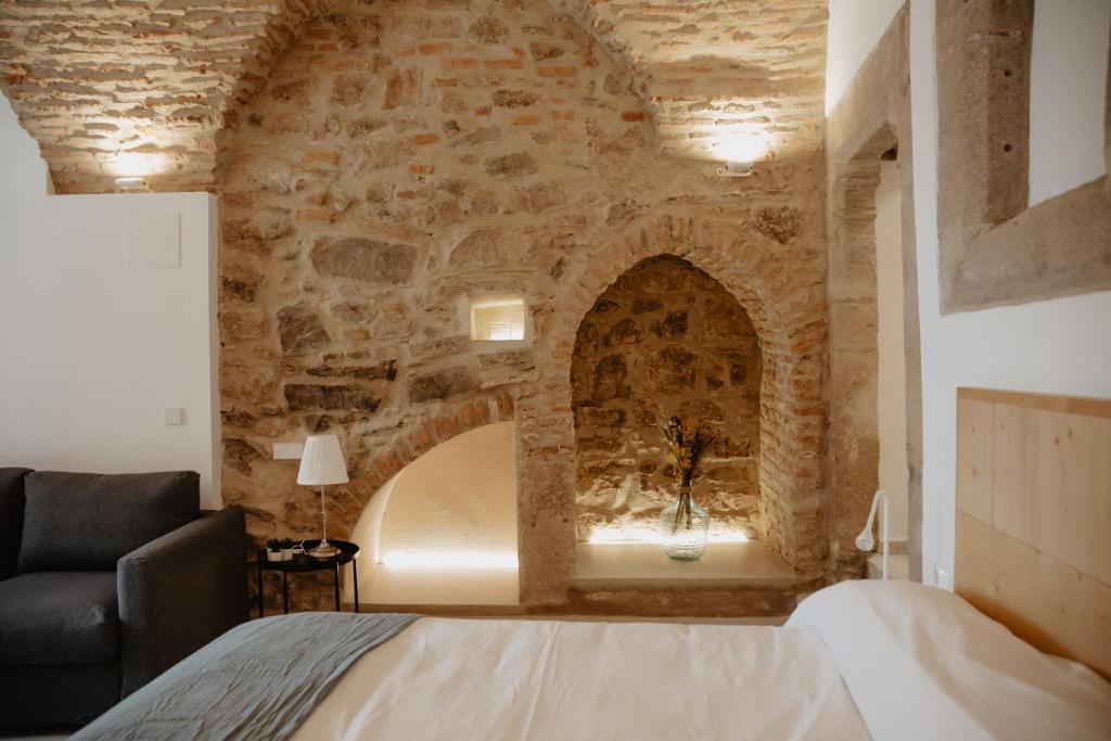 een slaapkamer met een bed en een stenen muur bij PORTAL DE SANTIAGO in Cáceres