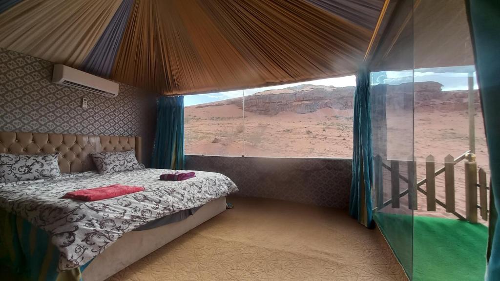 a bedroom with a bed and a view of the desert at Sultan Luxury Camp in Wadi Rum